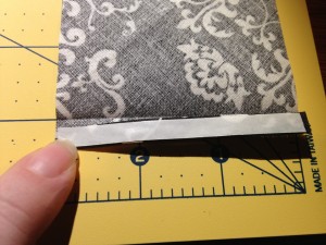 The narrow strip of iron-on adhesive is on the folded fabric.